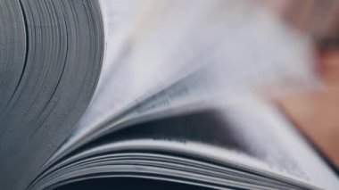 Kalın bir kitabın sayfalarını hızlıca çeviriyorum. Ayrıntılı görüş. Yakın plan. Kitap okumak.