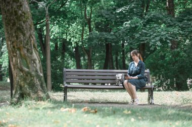 Güzel bir kadın parkta bir bankta oturur, kitap okur. Açık hava eğlencesi.