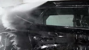 Manuel oto yıkama. Yakın plan. Yüksek basınçlı suyla siyah araba yıkama.