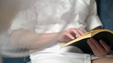 Bir kadın hayranının önünde oturmuş ilginç bir kitap okuyor. Bir el ve bir kitap yakın plan..