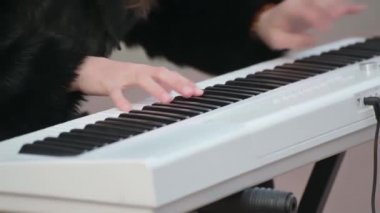 Çocuğun elleri sokakta piyano klavyesi çalıyor. Eller piyano tuşlarında, yakın plan..