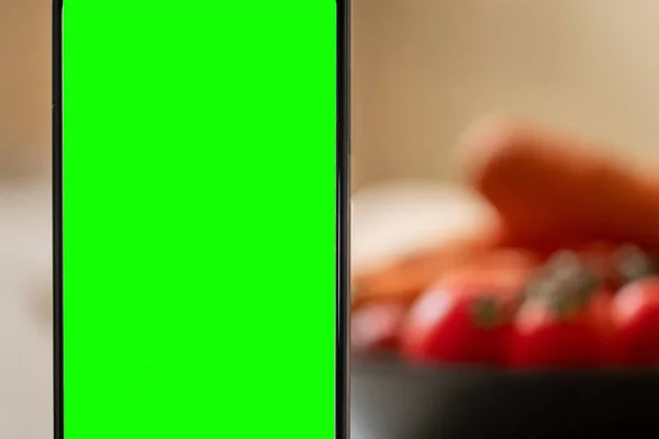 Smartfon Zielonym Ekranem Rozmytym Tle Talerza Warzywami — Zdjęcie stockowe