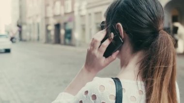 Yetişkin bir kadın sokakta dururken cep telefonuyla konuşuyor..