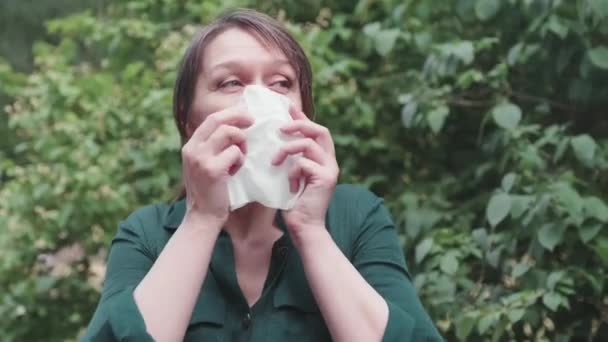 公園に咲く木の近くに鼻ワイパーを持つ大人の女性 アレルギーの概念 — ストック動画