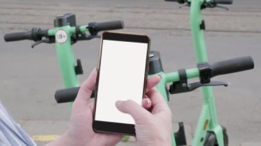 Bir kadın akıllı telefonuyla elektrikli scooter sipariş ediyor, at paylaşımı. Telefonu boş ekrana ver..
