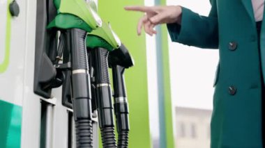 A woman fills up her car. green pistols at a gas station.  Petrol and Diesel.