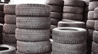 Lastik yığını arka planı. Bir depoda araba lastikleri üst üste yığılmış..