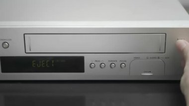 woman pull out VHS cassette from VCR. Video player and video cassette.