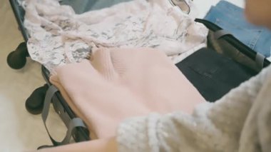woman traveler packing her clothes and things in a suitcase, going on a trip and vacation