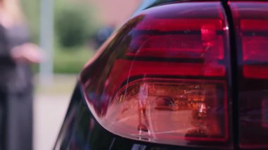 Flashing orange car headlight. The woman turns on the alarm in the car.