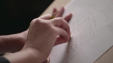 El çizimi. Sanatçının stüdyosunda kadın ressamın eli kalem tutarken ve resim çizerken yakın plan..