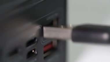 Close-up of a hand inserting a USB cable into a power supply or power bank.