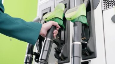 Refilling the car. At the gas station there are green pistols for refueling the car with gasoline.