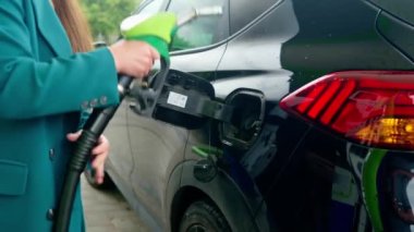 business woman's hand inserts a pistol into the tank to fill the car with gasoline or diesel fuel.