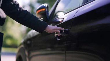 the woman opens the door and gets behind the wheel of her car.