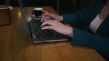 a lady sits in a cafe and typing on a laptop. Close-up of hands.