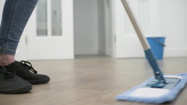 a woman washes the floor in a room at home with a flat wet mop.
