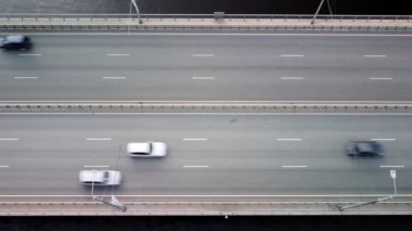 Flying over a modern highway bridge with heavy traffic across a wide river. Aerial view.