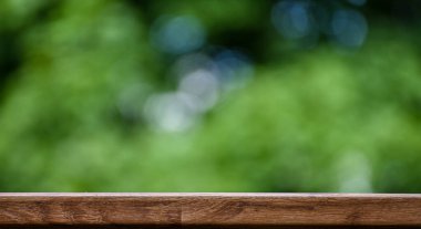 Bulanık yeşil arka planı olan boş ahşap bir raf. Tasarım şablonu.