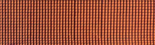 panorama of antique clay red roof tiles of an ancient house, close-up of the repeating wave pattern of orange clay roof tiles.