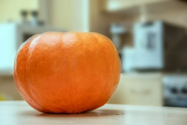 大きなオレンジのカボチャは ハロウィーンのために彫刻される準備ができてキッチンテーブルの上にあります お祝いの気分を作成するためにナイフでカボチャの提灯に恐ろしい顔を彫る — ストック写真