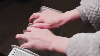 Evdeki elektrikli ısıtıcının yanında kadınların elleri ısınıyor. Isınma mevsimi konsepti