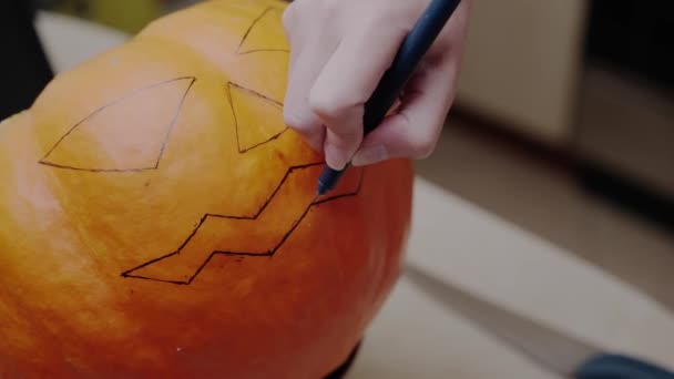 Kvinna Ritar Ett Skrämmande Ansikte Orange Pumpa Med Svart Markör — Stockvideo