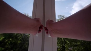 Eller, güneşli bir yaz gününde doğanın muhteşem manzarasına sahip bir pencereyi açar..