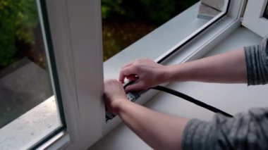 Soğuk mevsime hazırlanıyorum. Bir kadın pencereye siyah bir lastik bant yapıştırıyor..