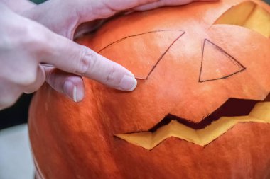 Bıçak oyma kabağı ya da evde balkabağı kullanan bir kadın. Balkabağı ve ellerin yakın çekimi. Cadılar Bayramı, dekorasyon ve tatil konsepti 