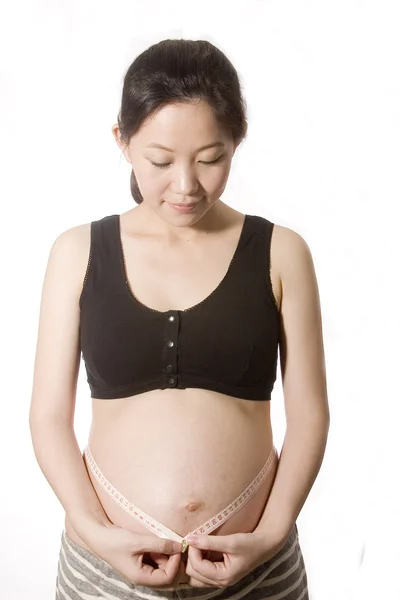 Pretty young pregnant woman is measure her waist — Stock Photo, Image