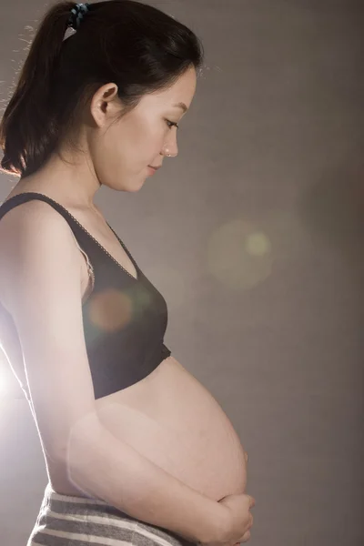 Hübsche junge schwangere Frau berühren ihren Bauch — Stockfoto