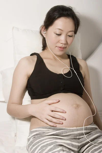 Junge schwangere Frau spielt iPod — Stockfoto