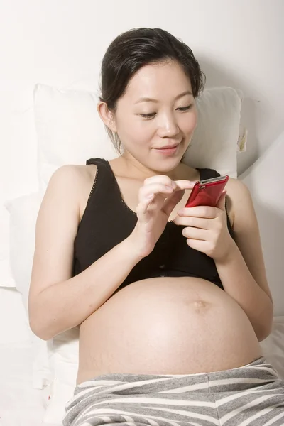 Junge schwangere Frau spielt iPod — Stockfoto