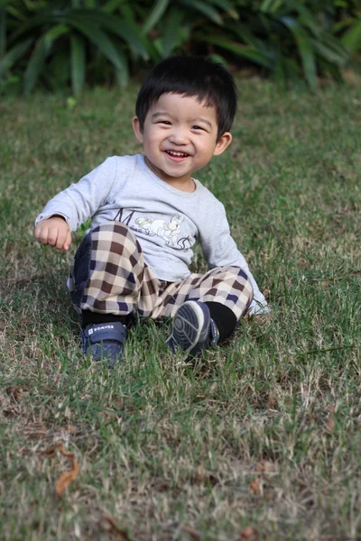 Feliz ásia menino sentado no um grama — Fotografia de Stock