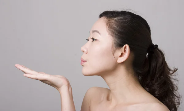 An Asian girl blowing something on her hand — Stock Photo, Image