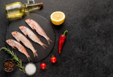 Baharatlı çiğ balık ve siyah taş arka planda bitkiler. en üstteki görünüm.