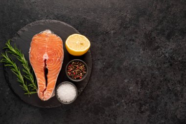 Baharatlı çiğ balık ve siyah taş arka planda bitkiler. en üstteki görünüm.