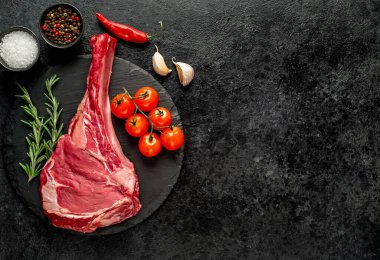 Baharatlı çiğ et ve siyah arka planda bitkiler