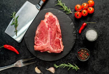 Biberiyeli çiğ biftek ve siyah arka planda kekik.