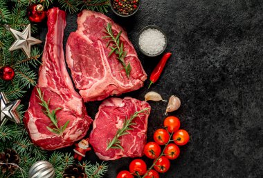 Baharatlı çiğ biftek ve siyah arka planda otlar.