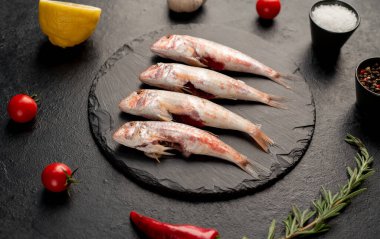 Siyah zemin üzerinde limonlu çiğ balık ve biberiye.