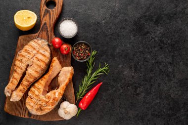 Baharatlı ızgara somon bifteği ve siyah taş arka planda otlar. Üst Manzara. Metnin için boş yer