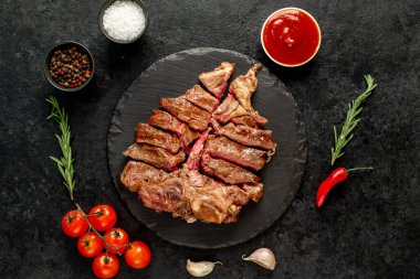 Siyah arka planda ızgara biftek, sebze ve baharat.