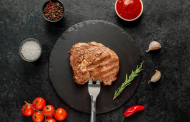 Domates soslu ızgara biftek ve siyah arka planda baharatlar. en üstteki görünüm.