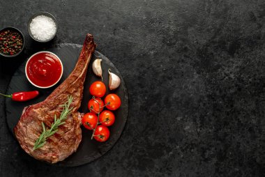Biberiyeli ızgara biftek ve siyah arka planda baharatlar.
