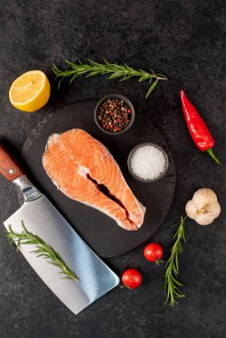 Biberiyeli çiğ somon filetosu ve siyah taş arka planda baharatlar. en üstteki görünüm.
