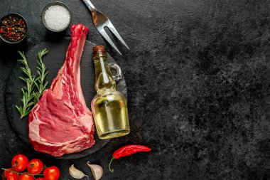 Baharatlı çiğ et ve siyah arka planda bitkiler