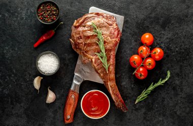 Baharatlı ızgara biftek ve siyah arka planda otlar.