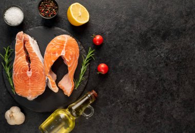 Sebzeli çiğ somon filetosu ve siyah taş arka planda baharatlar. en üstteki görünüm.